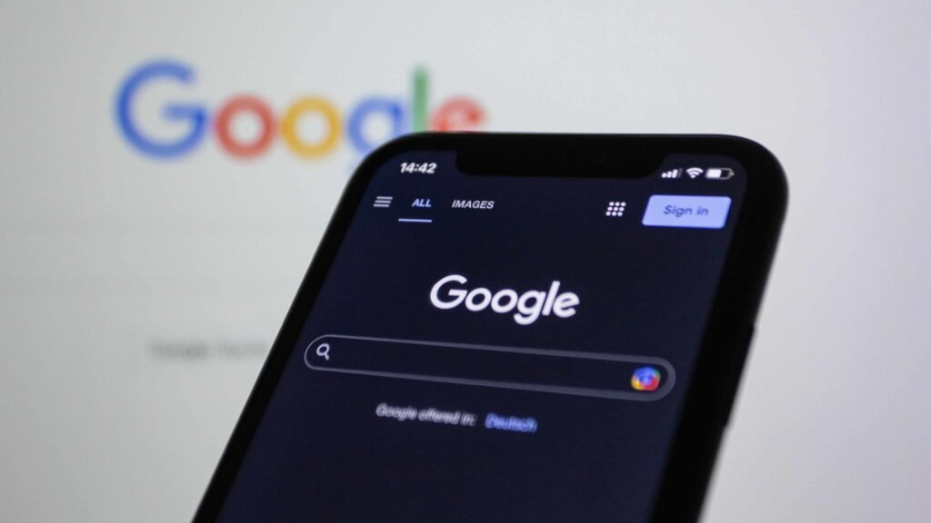 Smartphone and monitor displaying the google interface, highlighting how businesses can improve brand visibility in ai search engines.