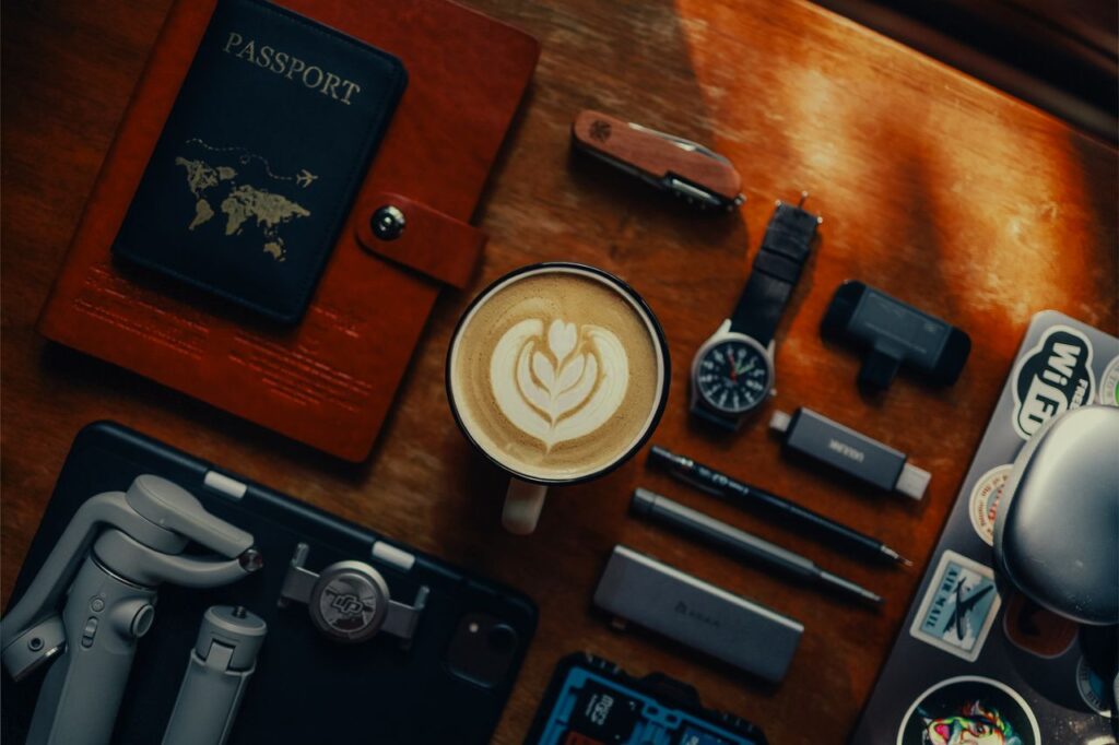 Passport in a leather cover on a wooden desk beside a cup of coffee and personal devices