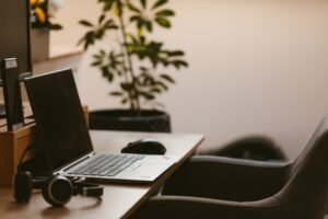 A laptop and headphones on a wooden desk in a quiet home office