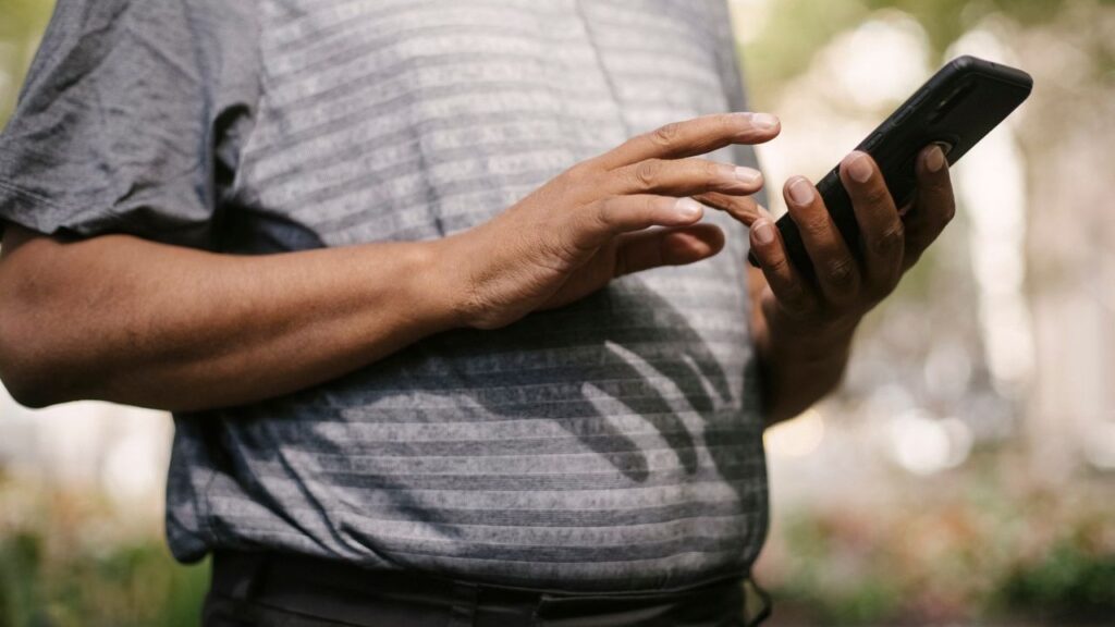 Man tapping the screen of a smartphone outdoors